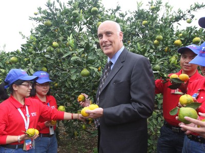 沃爾瑪中國公司事務高級副總裁博睿（中）考察大理項目基地，并同沃爾瑪員工志愿者一起幫助受助農戶收獲成熟的柑橘。